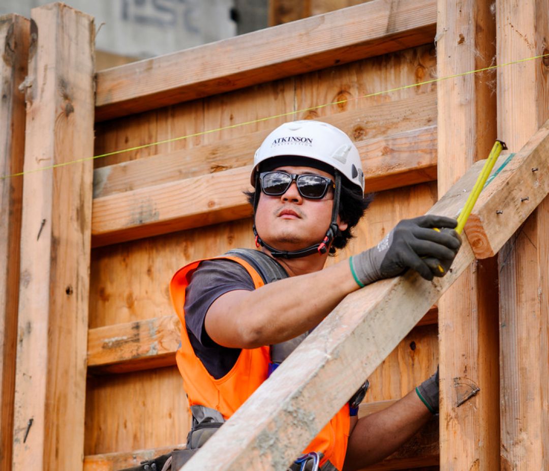 Atkinson Construction team member wearing full PPE against a wooden background
